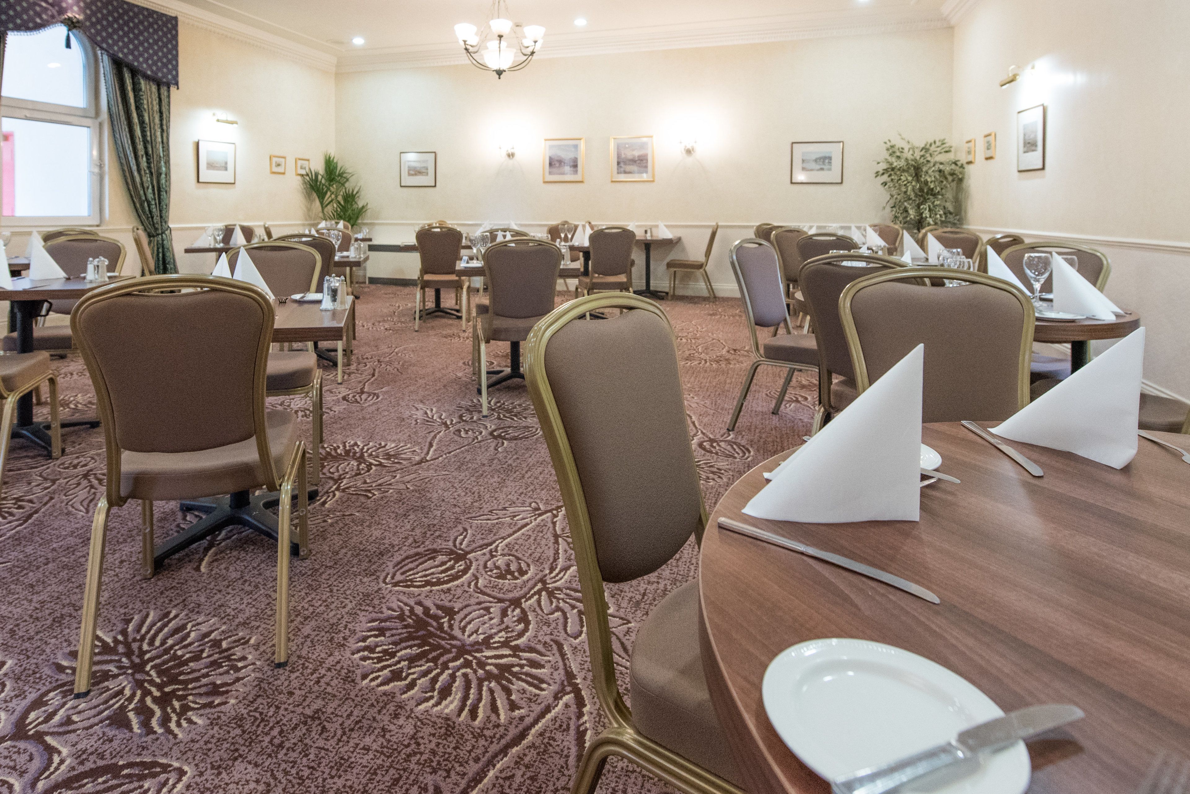 A conference room with round tables, chairs, and a carpeted floor.