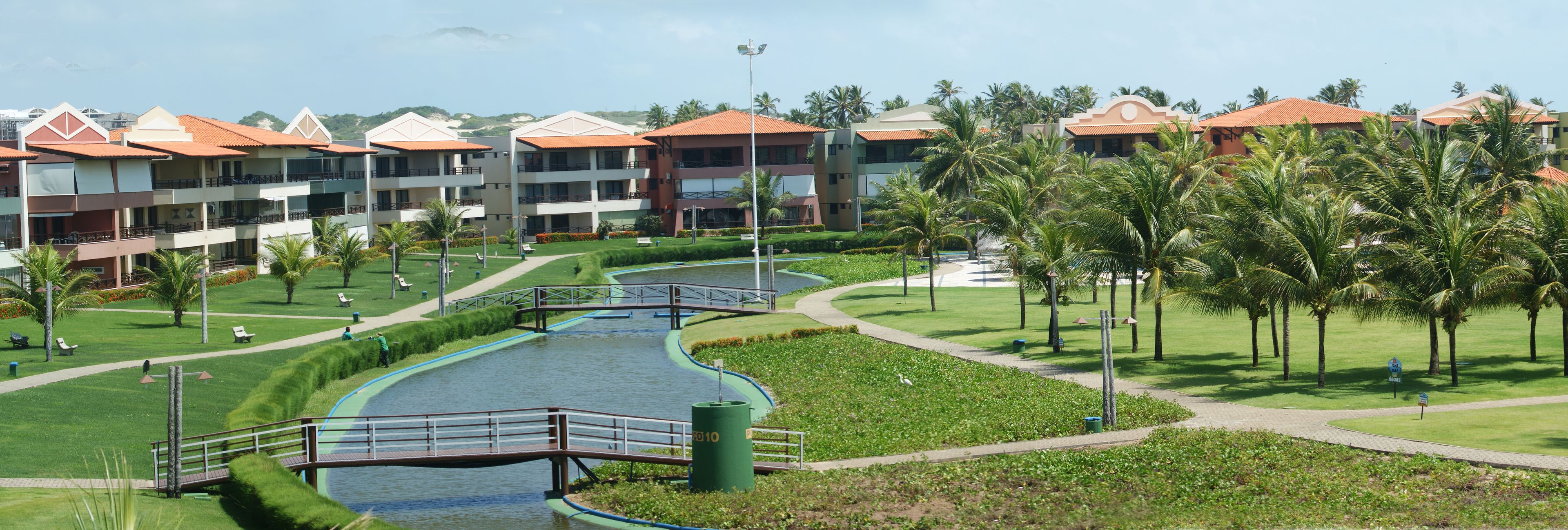 A resort with multiple-story buildings, a central water feature, and palm trees.