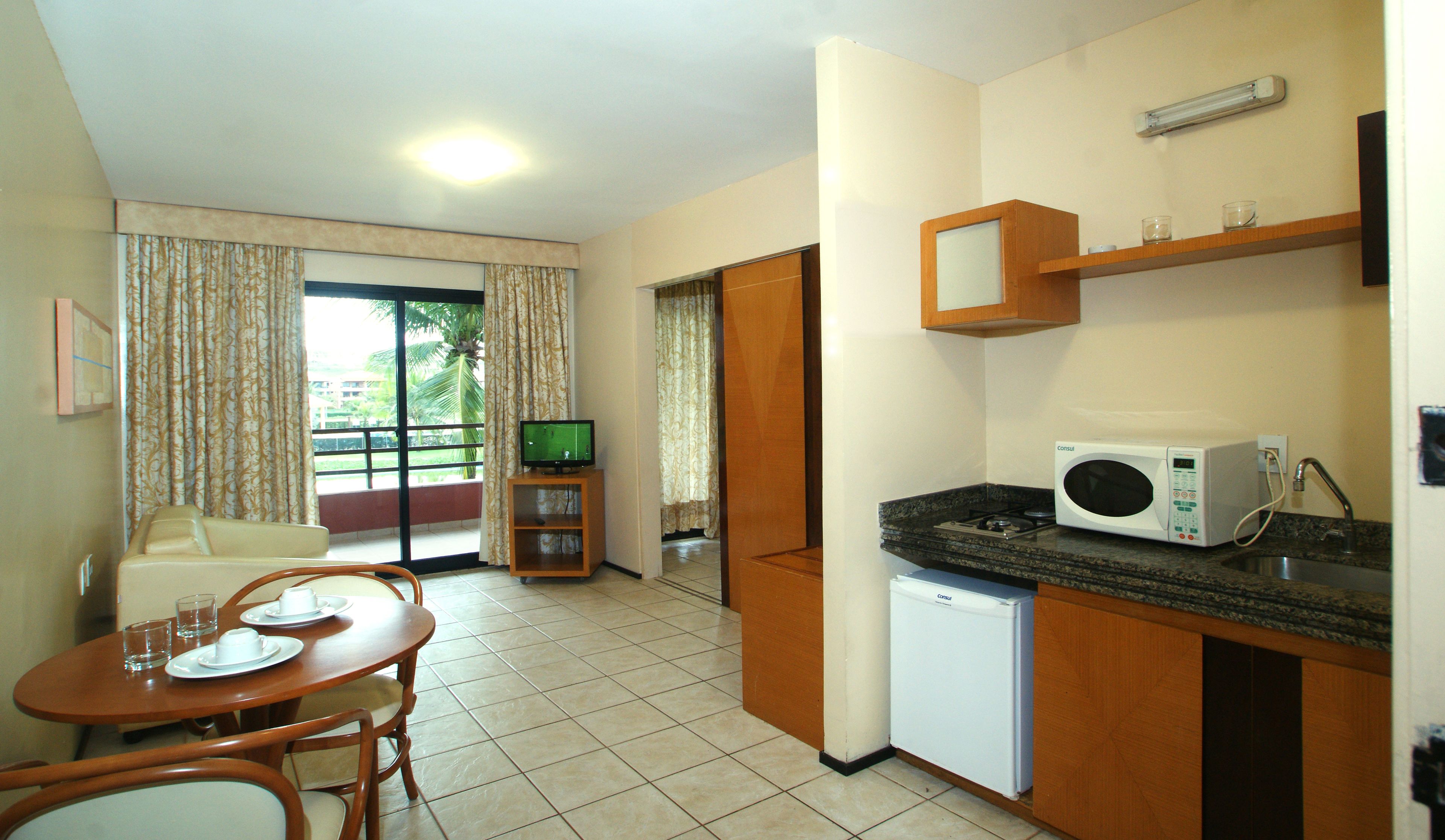 A compact kitchen with a microwave, a small refrigerator, and a dining area with a table and chairs.