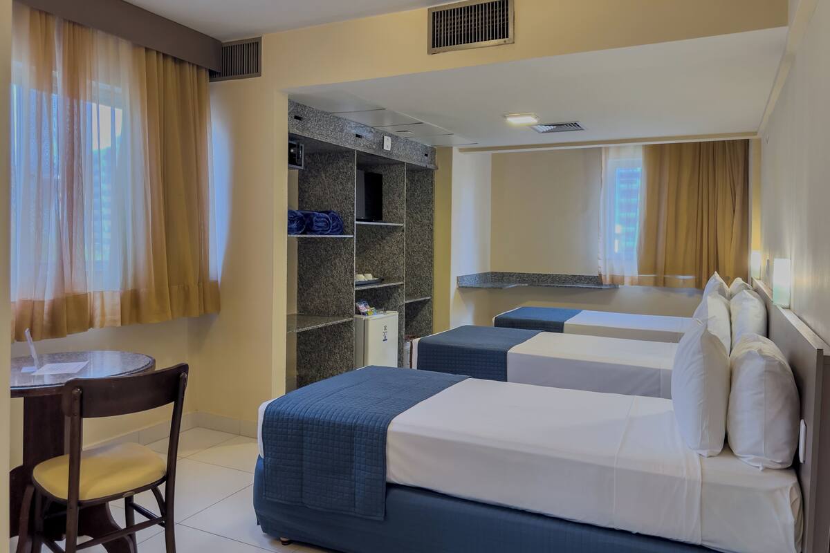 Een hotelkamer met twee bedden, een bureau, een stoel, een kledingkast en een spiegel.