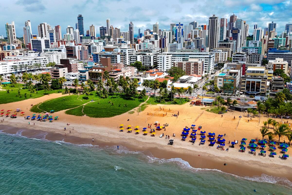 Een kuststadsbeeld met een strand, palmbomen en een dichtbebouwde skyline.