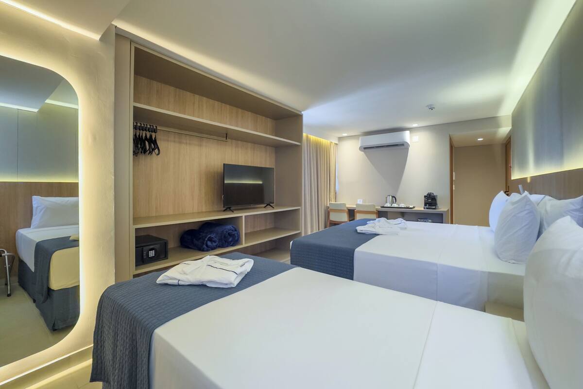 Een hotelkamer met twee bedden, een televisie, een bureau met koffiezetapparaat en een kledingkast.