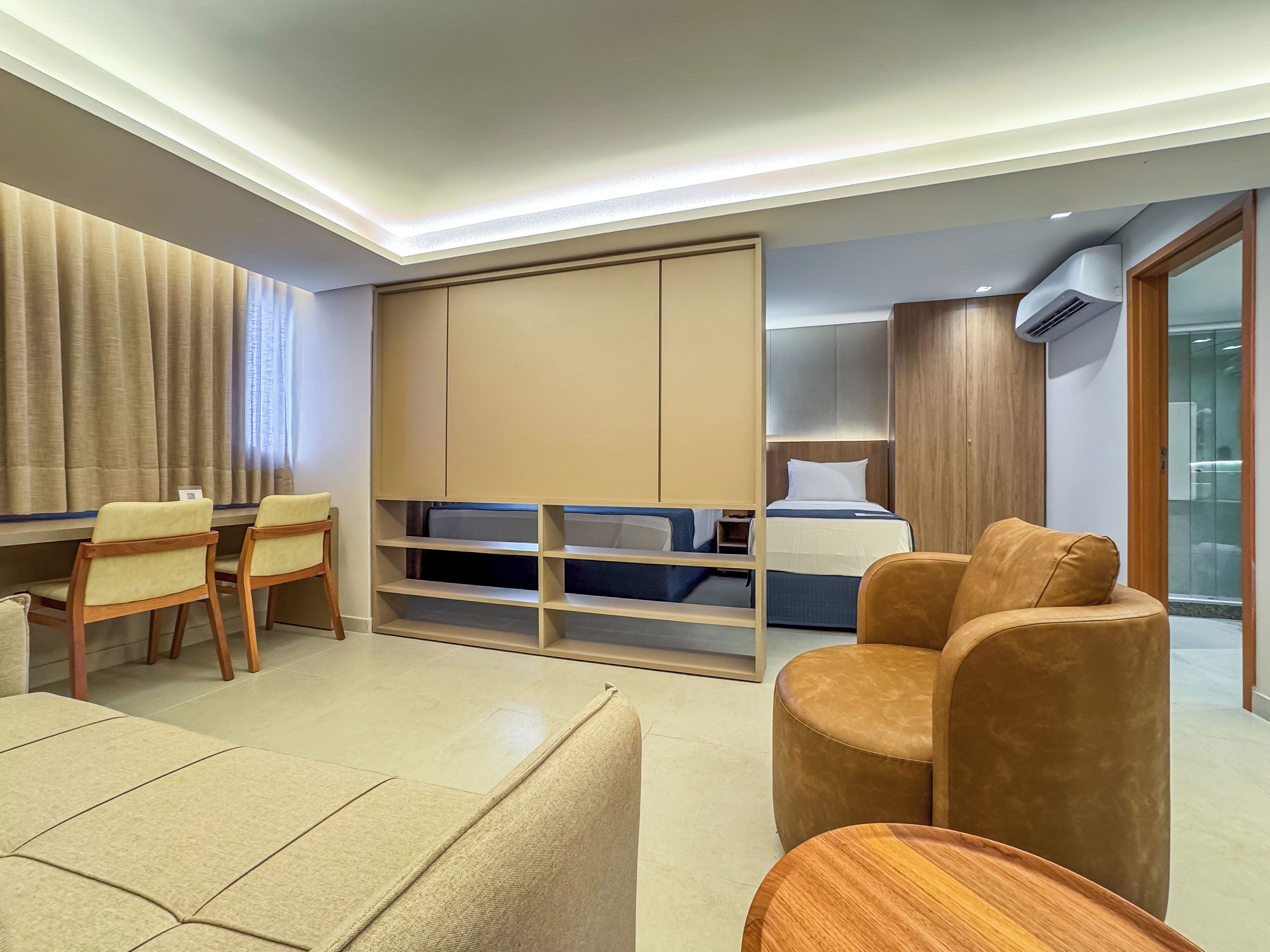 A modern hotel room with a bed, a desk, and a seating area.
