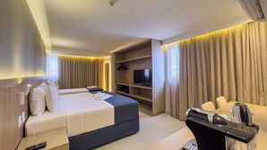 Una habitación de hotel con cama, escritorio con cafetera, televisor y armario.