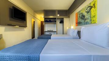 Habitación de hotel con dos camas, televisión, armario y un cuadro en la pared.