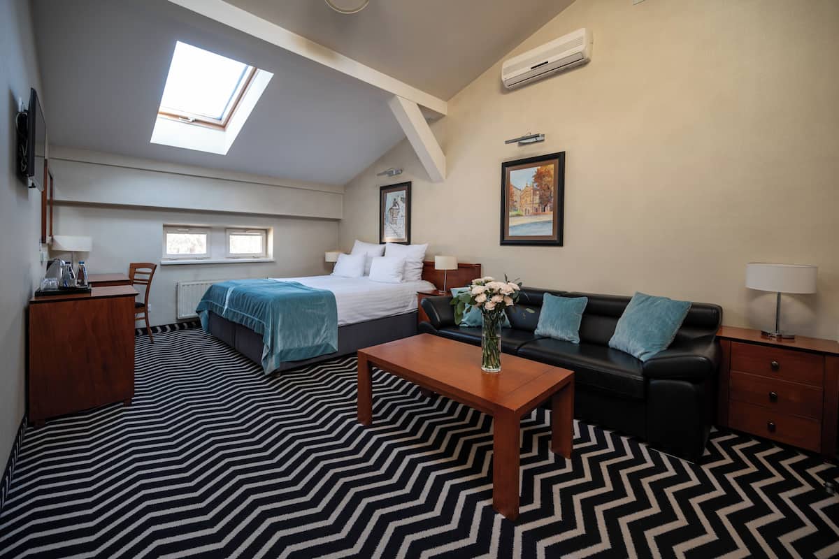 Ein Hotelzimmer mit Bett, Sofa, Schreibtisch, Sessel, Couchtisch und Fenster.
