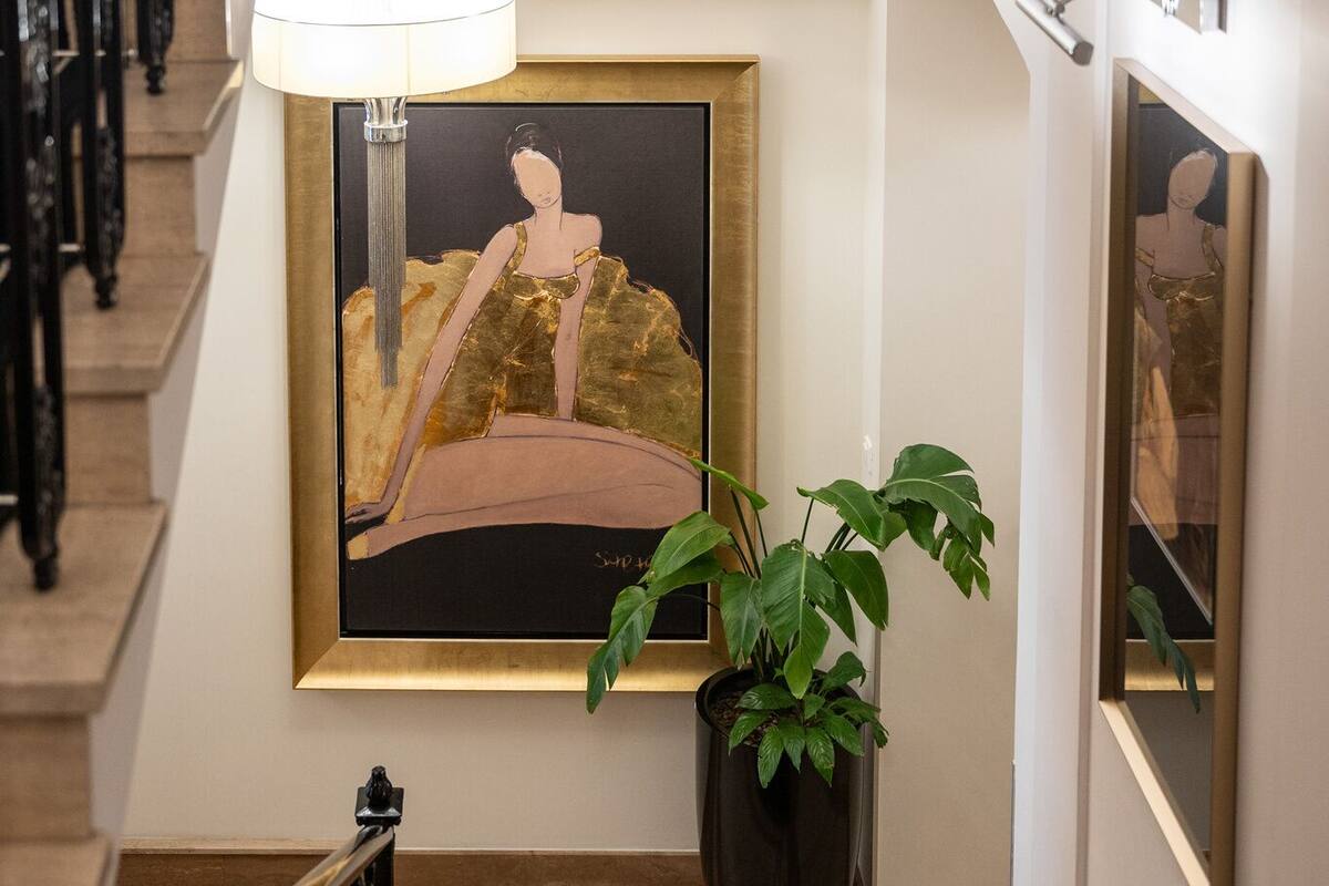 Eine Treppe mit einem gerahmten Kunstwerk, einer Topfpflanze und einer Hängelampe.
