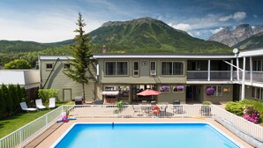 A two-story building with a swimming pool, outdoor seating, and mountain views. - Powder Mountain Lodge (Fernie)