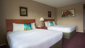A hotel room with two beds, a nightstand with a lamp, and two framed pictures on the walls. - Powder Mountain Lodge (Fernie)