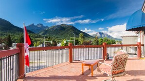 A balcony with a view of mountains, a flag, and outdoor furniture. - Powder Mountain Lodge (Fernie)