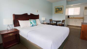 Habitación de hotel con una cama grande, mesitas de noche, una pequeña mesa de comedor y una kitchenette.