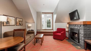 A modern living room with a fireplace, a television mounted on the wall, and a red armchair.