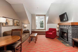 Una sala de estar moderna con chimenea, un televisor montado en la pared y un sillón rojo.