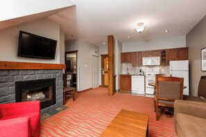A modern living room with a fireplace, a flat-screen TV, and a red armchair.