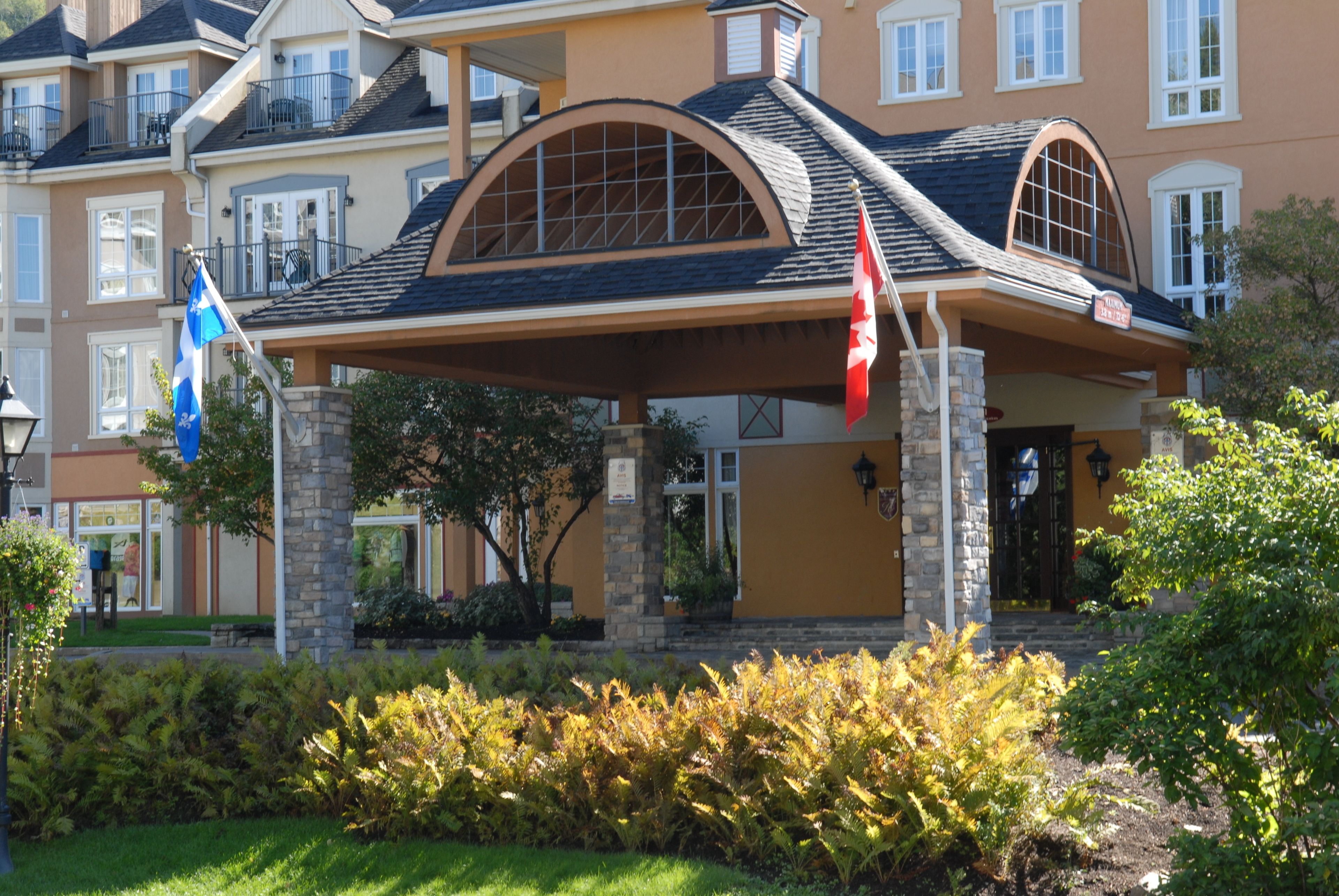 A multi-story hotel with a covered entrance, stone pillars, and a flag.