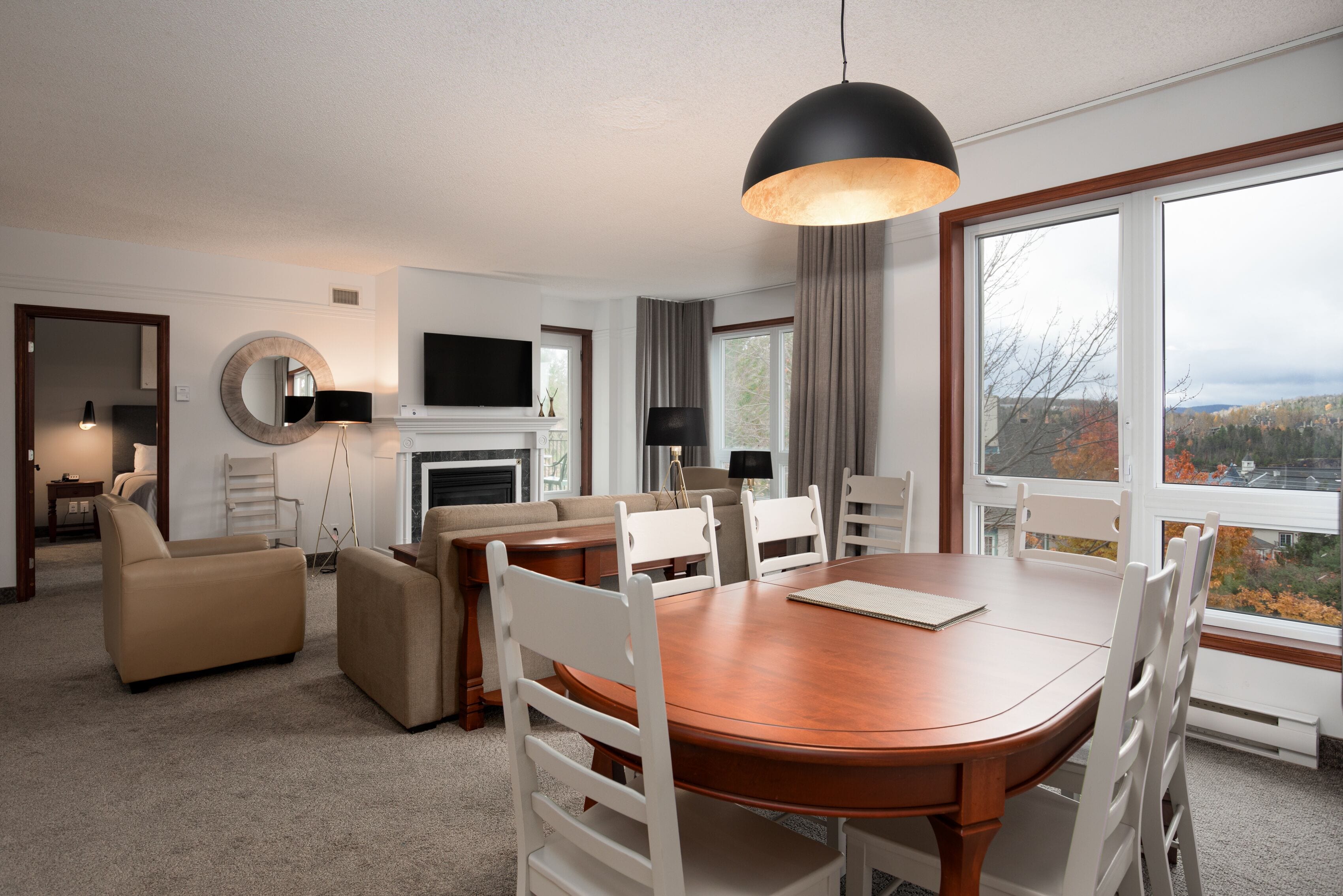 Een moderne hotelkamer met een zithoek, een zetteleefruimte, een open haard en een groot raam met uitzicht op de stad.