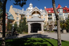 A hotel with a central entrance, multiple balconies, and a distinctive tower. - Sommet des Neiges (Mont-Tremblant)