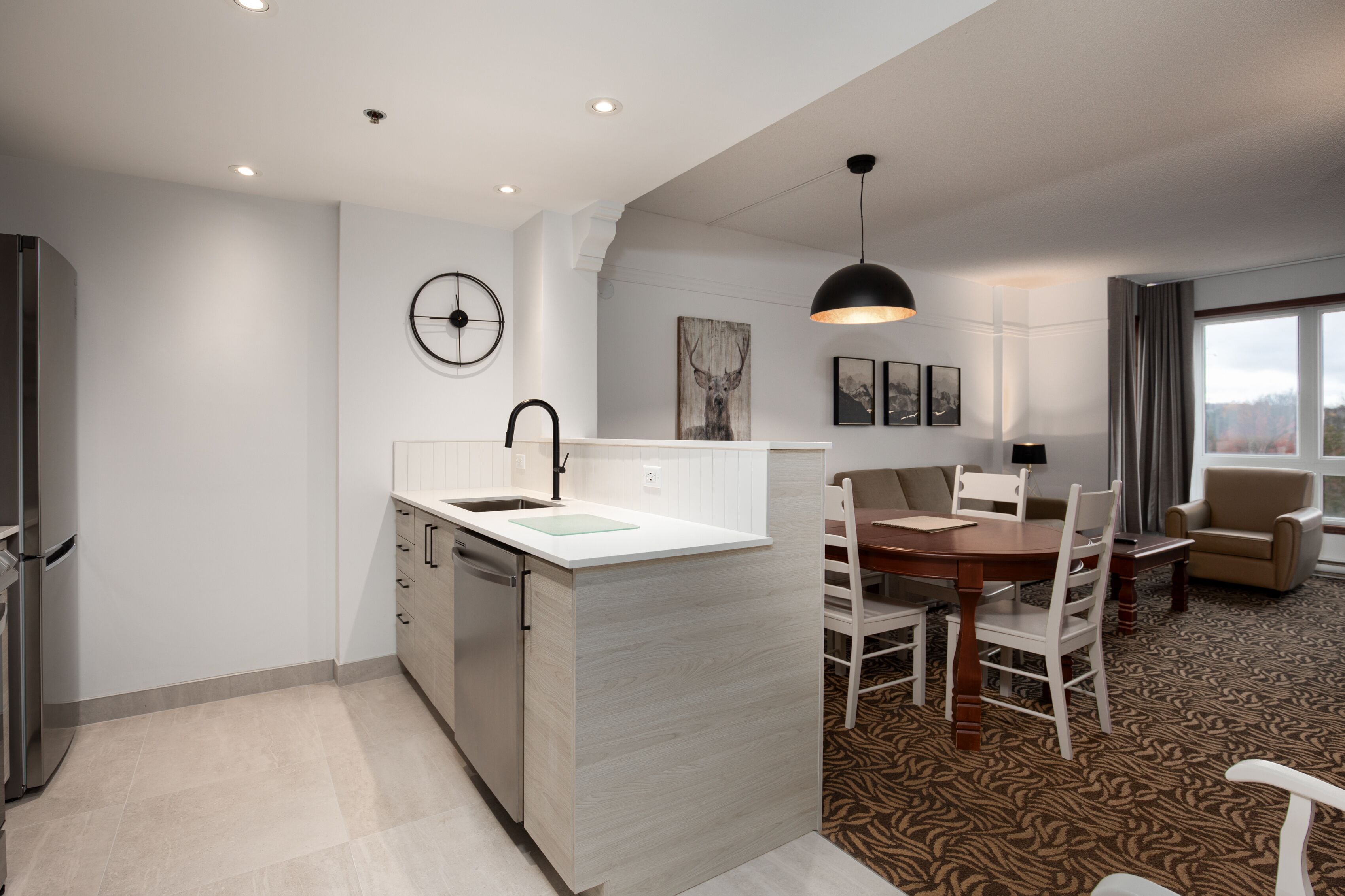 Una cocina moderna con lavavajillas integrado, un comedor con mesa y sillas de madera, y un ventanal con vistas.