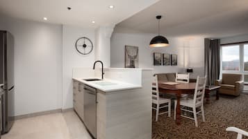 Una cocina moderna con lavavajillas integrado, un comedor con mesa y sillas de madera, y un ventanal con vistas.