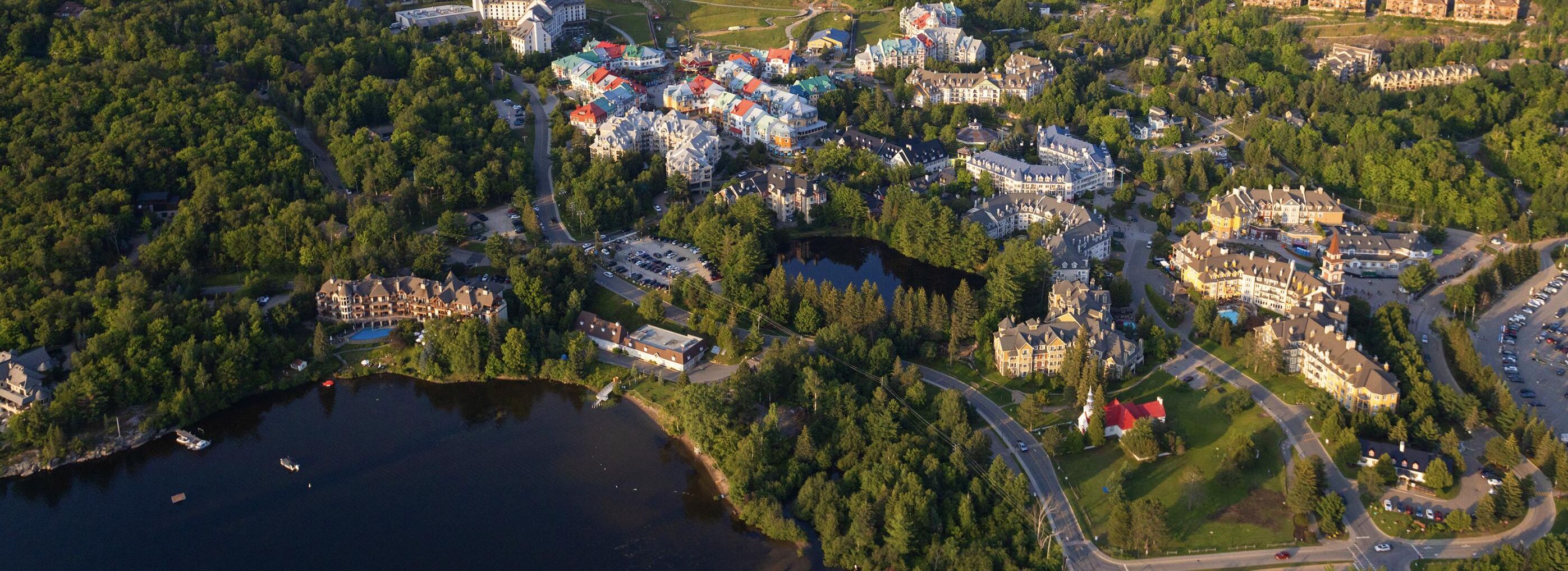 Luchtfoto van een vakantiecomplex aan een meer, met meerdere gebouwen, wegen en een steiger.
