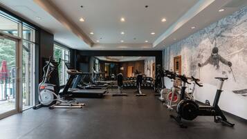 Een sportschool met diverse fitnessapparaten, waaronder loopbanden, hometrainers en krachtapparaten.