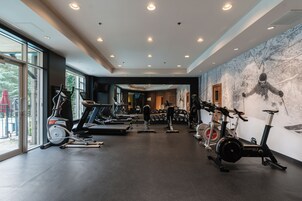 Un gimnasio con diversos equipos de ejercicio, incluyendo cintas de correr, bicicletas estáticas y máquinas de pesas.