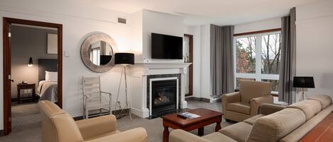 Una habitación de hotel moderna con chimenea, televisor de pantalla plana, sofá y mesa de comedor.
