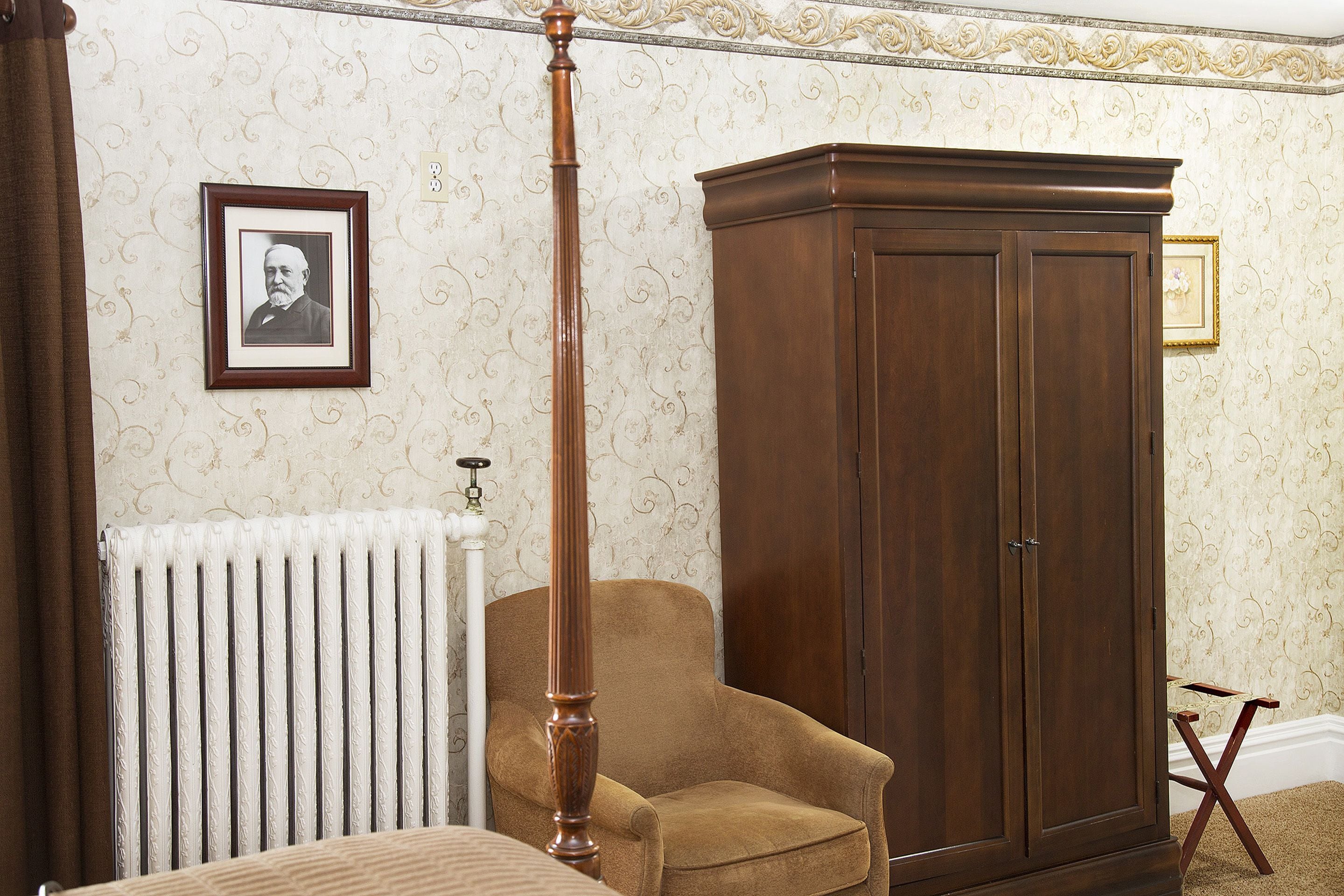 A room with a radiator, a wooden chair, and a large wooden wardrobe.