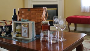 A wooden table with a bottle, a basket, jars, and wine glasses. - Kearsarge Inn (North Conway)