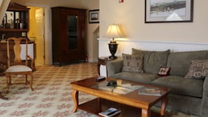 A living room with a wooden coffee table, a sofa, a lamp, and a framed picture on the wall. - Kearsarge Inn (North Conway)