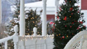 A white porch with a bench, a Christmas tree, and a railing. - Kearsarge Inn (North Conway)