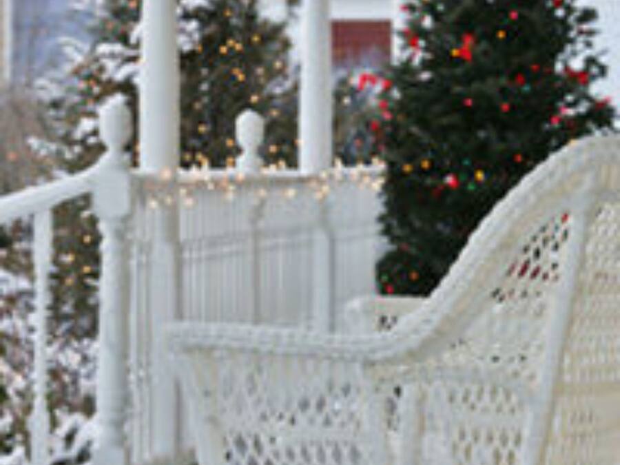 Un portico bianco con una panchina, un albero di Natale e una ringhiera.