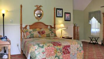 A bedroom with a wooden bed, floral bedding, a mirror above the bed, and a lamp on a bedside table.
