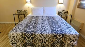 A bed with a patterned bedspread, two wall-mounted lamps, and a radiator.