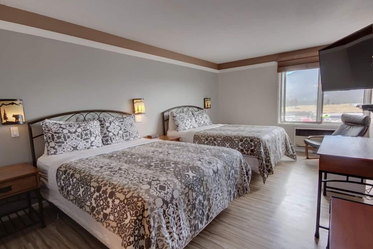 Une chambre d’hôtel avec deux lits, un bureau et une télévision.