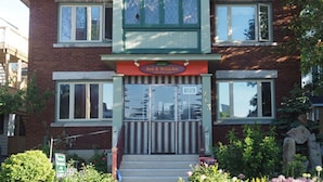A two-story building with a green and white facade, a sign reading "Bed & Breakfast," and a small front garden with flowers. - Downtown Bed and Breakfast (Ottawa)