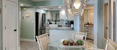 A modern kitchen with white cabinetry, a central island, and a chandelier.