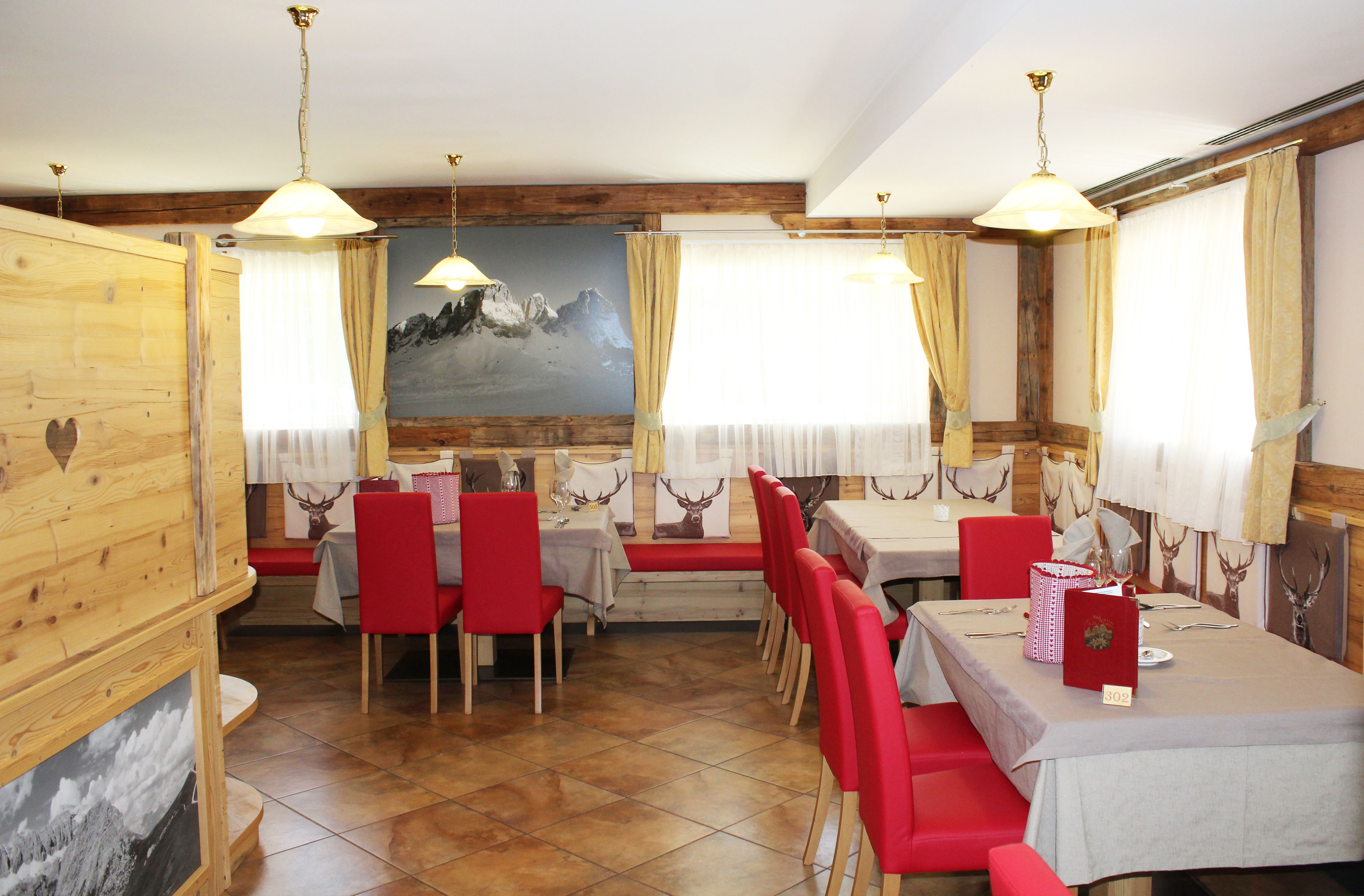 A dining area with wooden walls, red chairs, and tables set for a meal.