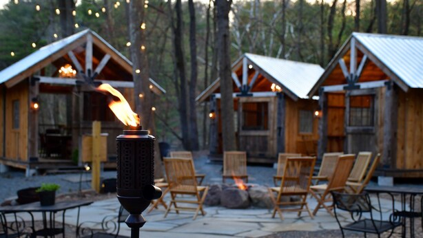 A rustic cabin-style hotel with outdoor seating and a fire feature.