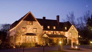 A large, two-story building with a steeply pitched roof, multiple windows, and a well-lit facade.