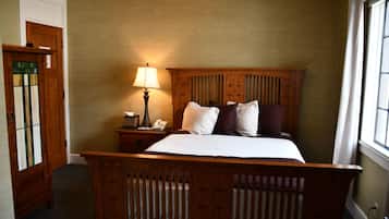 A bedroom with a wooden bed, a nightstand with a lamp, and a door with stained glass.