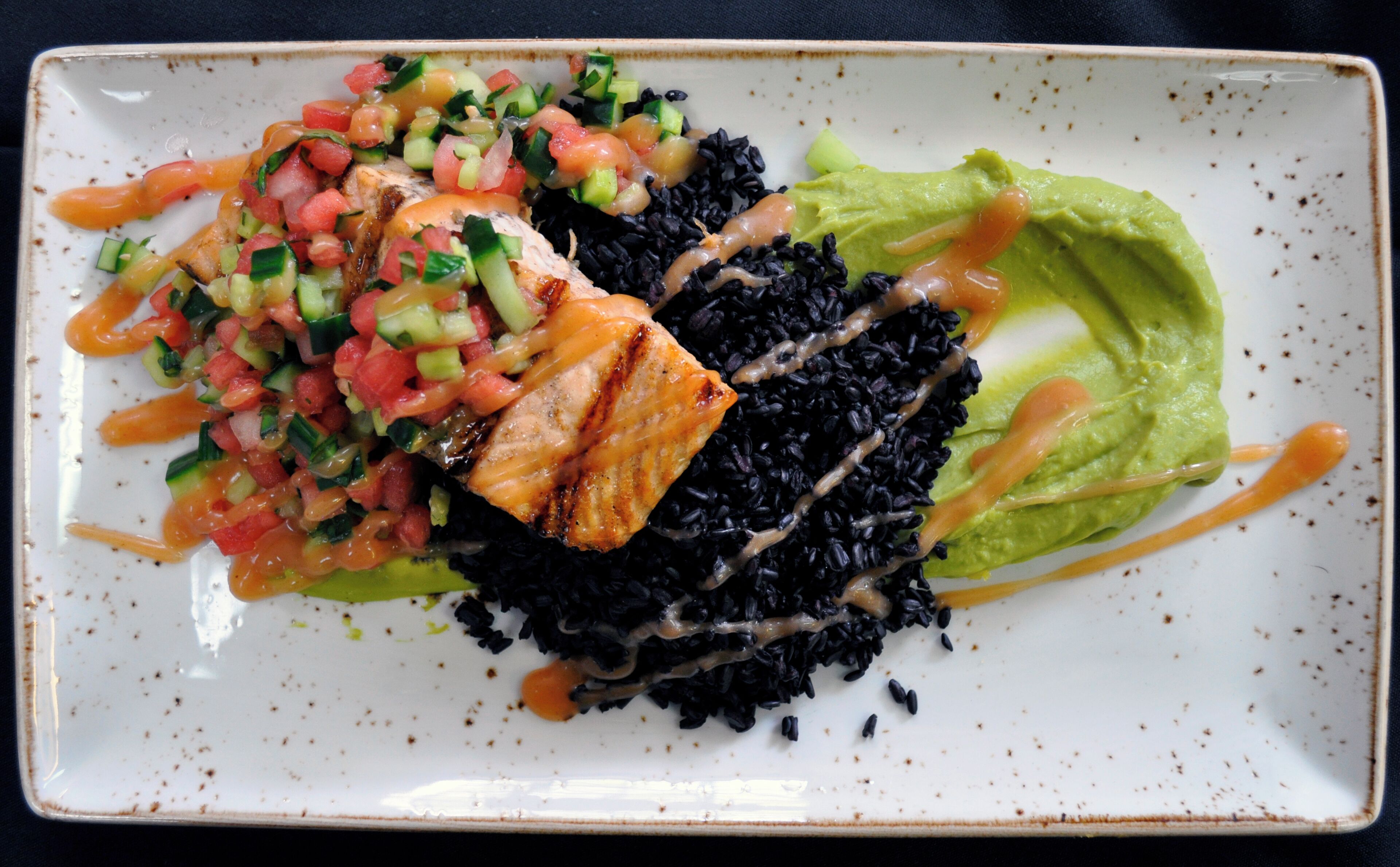 A plate with black rice, grilled chicken, a green salad, and a side of salsa.