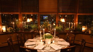 A restaurant with a round table set for a meal, candles, and potted plants.