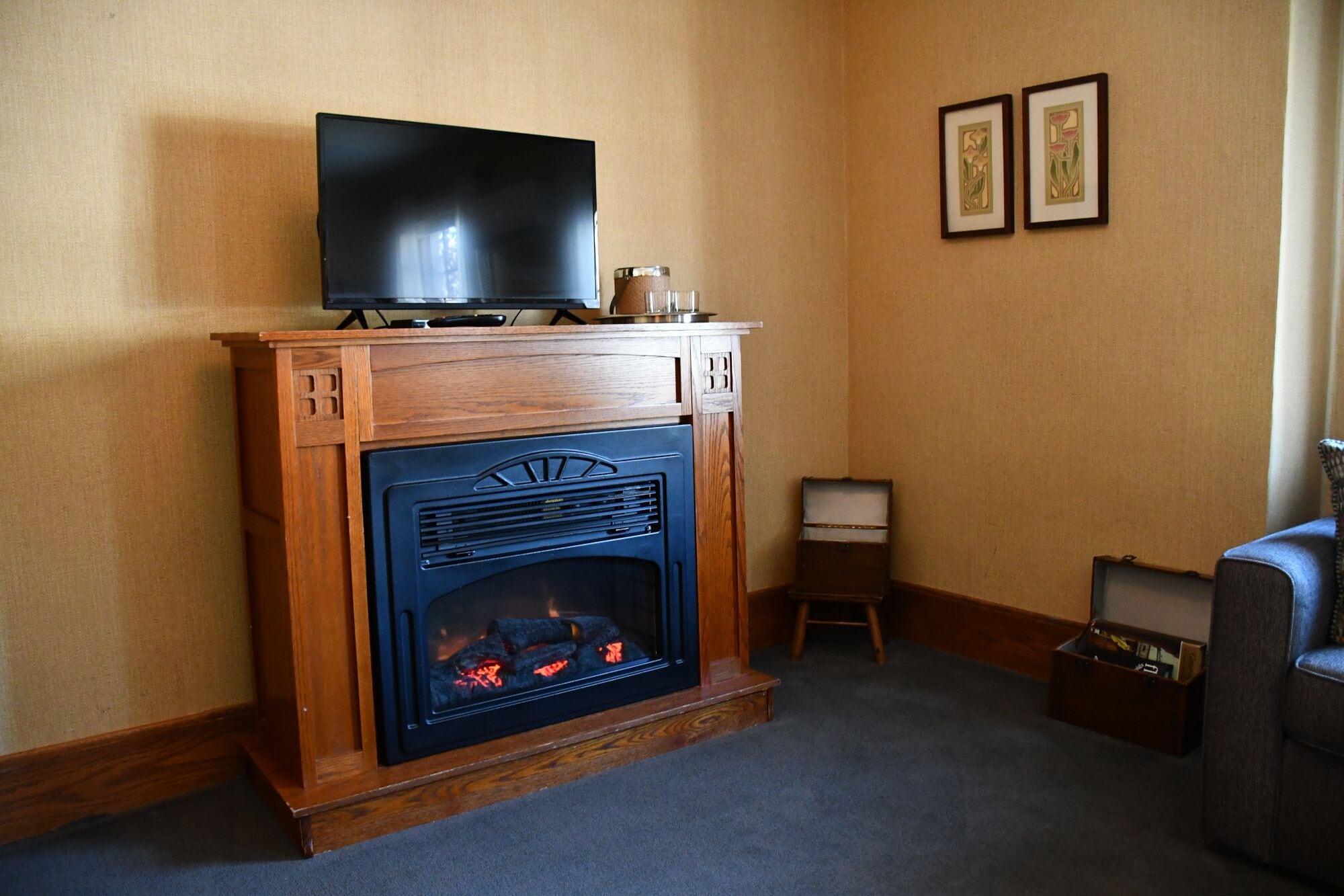 Una habitación con chimenea, un televisor encima y dos cuadros en la pared.