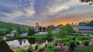 A serene lakeside property with a pond, surrounded by lush greenery and a variety of trees.