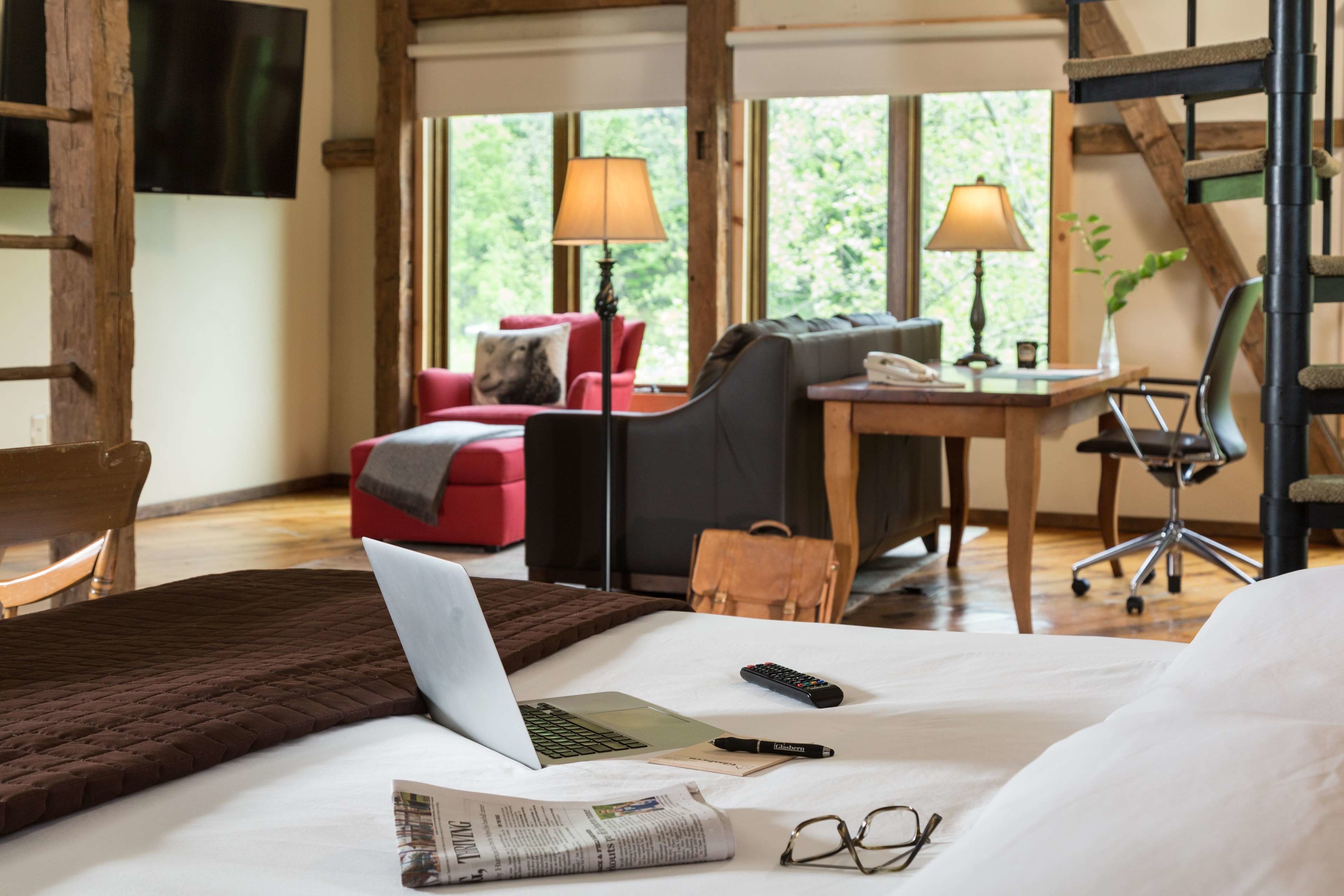 Quarto de hotel com cama, escrivaninha, cadeira, sofá e televisão.