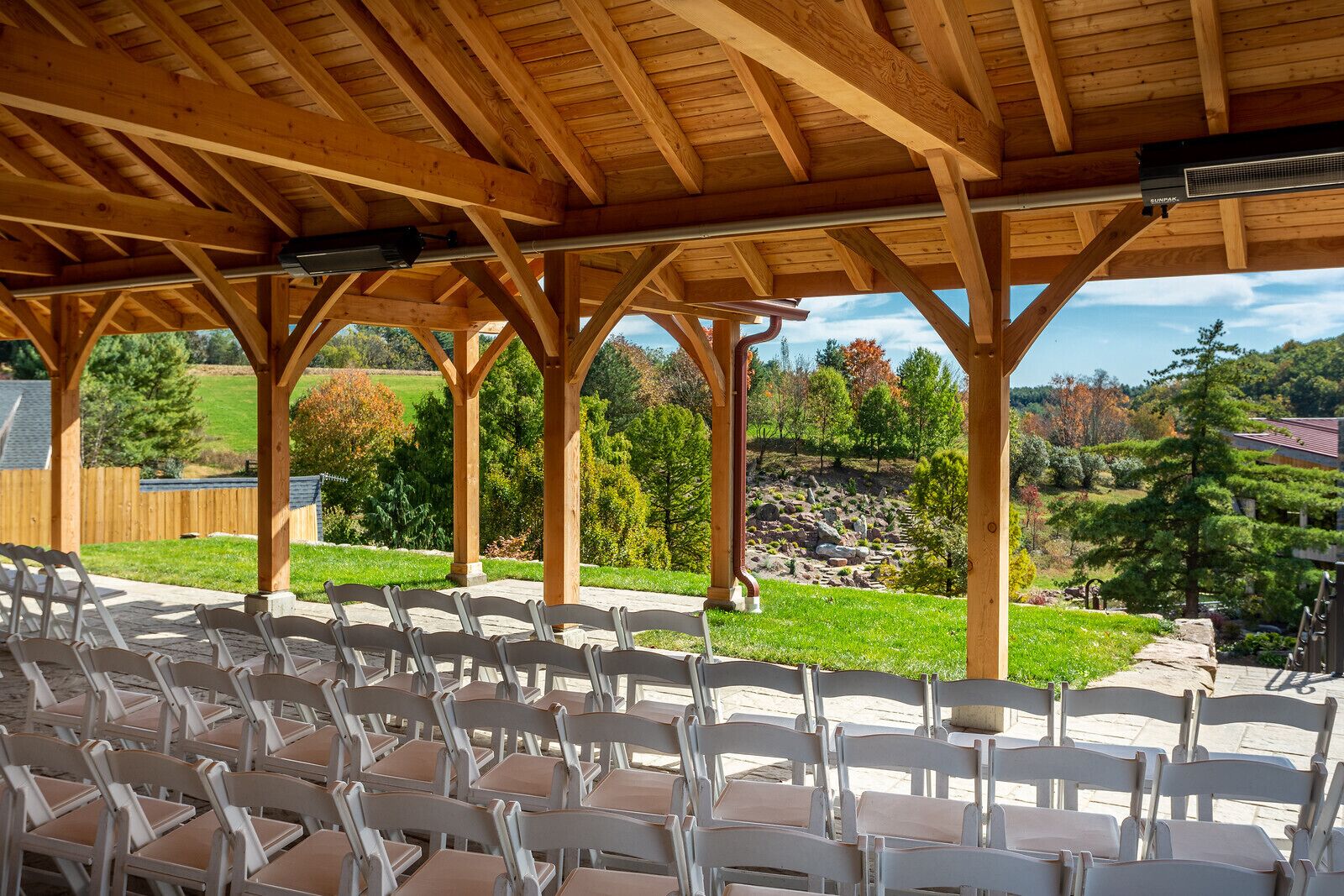 Un espace extérieur abrité, aménagé avec des rangées de chaises et offrant une vue sur un paysage naturel.