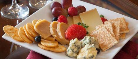 Een bord met kaas, crackers, aardbeien, druiven en een blauwe kaasdip op een wit bord.