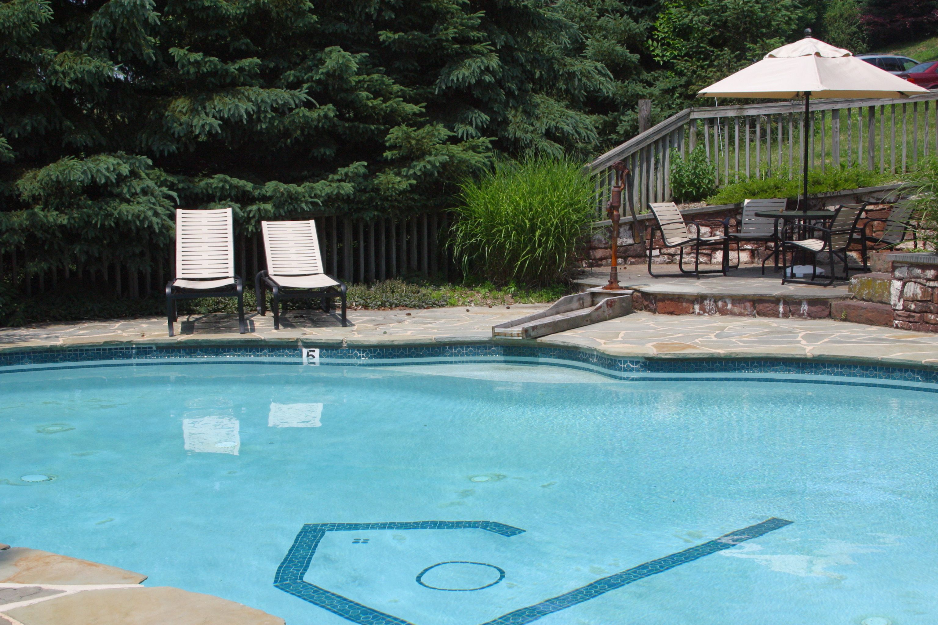 A swimming pool with lounge chairs and a covered patio area.