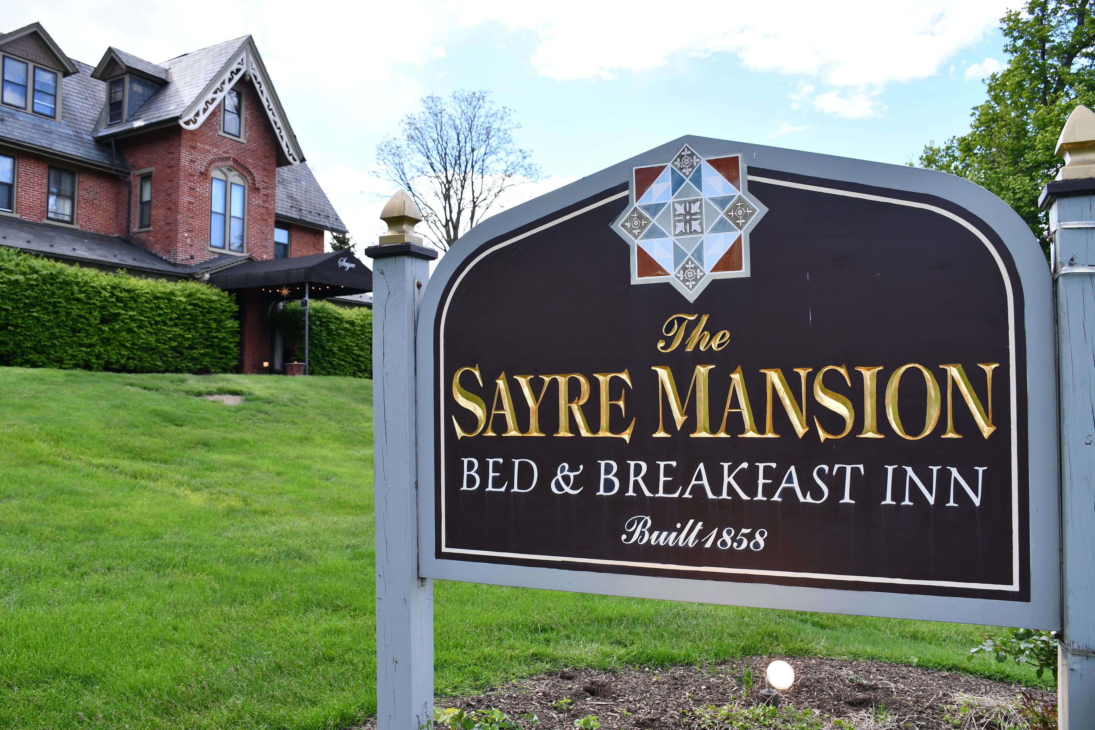 Letrero de The Sayre Mansion Bed & Breakfast Inn, construido en 1858, con un estilo arquitectónico clásico y un césped bien cuidado.
